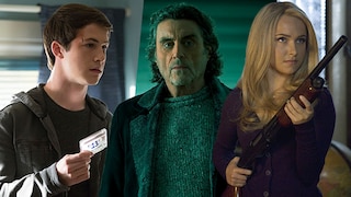 Three people stand side by side indoors. On the left, one person holds a cassette. In the middle, a person wearing a gray sweater and dark coat stands. On the right, a person with long blonde hair holds a shotgun. The background is lit in greenish and bluish tones.