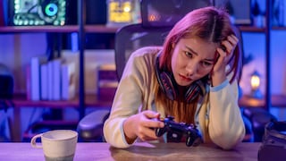 A gamer sits disappointedly at her desk with a controller in hand.