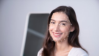 A woman smiles at the camera as her face is scanned.