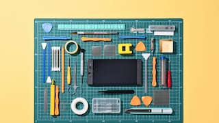 A broken smartphone lies on a repair surface surrounded by tools.