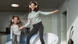 Two girls dance to music on the bed