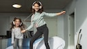 Two girls dance to music on the bed
