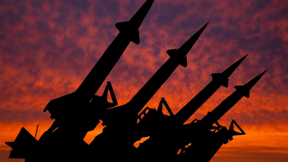 Silhouette of weapon-capable missiles against a sunset-drenched red sky