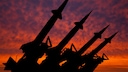 Silhouette of weapon-capable missiles against a sunset-drenched red sky