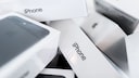 Several white iPhone boxes are stacked on top of each other. Some of the boxes display the Apple logo and the word "iPhone." The photo captures the boxes up close with a blurred background.