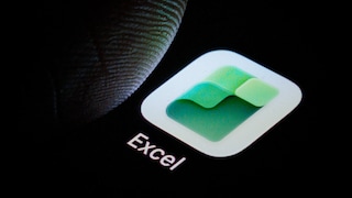 Close-up of a smartphone display featuring the Excel app. The green-and-white Excel logo is visible against a black background. To the left, a finger is either hovering over or touching the app. Below the icon, the word "Excel" is displayed.