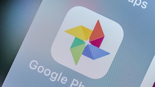 Close-up of the Google Photos app icon on a smartphone display. Below the colorful logo, the text "Google Photos" is visible.