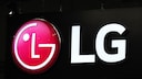 A glowing LG logo on a black billboard. On the left is the round red-and-white company logo, and to the right are the large white letters "LG" against a dark background.