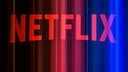 Abstract image of the red Netflix logo against a dark background with vertical light streaks in red, pink, and blue.