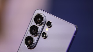 Close-up of the back of a silver Samsung smartphone with multiple camera lenses against a blurred blue-violet background