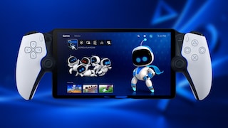 Portable gaming device with a large display and white controls on both sides, styled like a PlayStation controller. The screen shows the PlayStation interface with the game "ASTRO'S PLAYROOM." Several white robot figures are displayed on the screen, alongside a larger robot figure with glowing blue eyes. The background features various shades of blue and blurred PlayStation symbols.