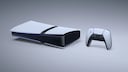 White PlayStation gaming console with a black center section on a light, neutral background. To the right is a white and black controller. The console is positioned horizontally, displaying several ports on the front. A narrow blue light strip is visible along the edge of the casing.