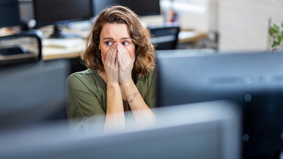 Woman Sits in Front of Monitor, Looking Shocked
