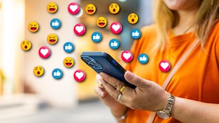 A woman uses her smartphone, with various emojis symbolically appearing above it.