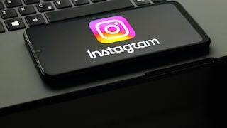 The Instagram logo is visible on a smartphone, which is resting on a laptop keyboard.