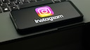 The Instagram logo is visible on a smartphone, which is resting on a laptop keyboard.