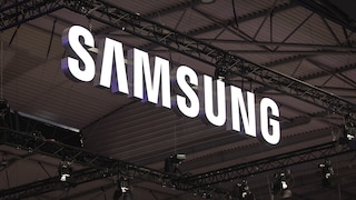 Large illuminated Samsung logo under a ceiling with metal beams and event technology