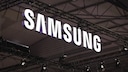 Large illuminated Samsung logo under a ceiling with metal beams and event technology