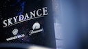 Large display board with the inscription "Skydance" and the logos of Warner Bros. and Paramount against a dark background.