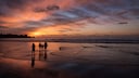 Family with children on the beach at sunset