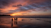 Family with children on the beach at sunset