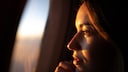 Young woman looks out of the airplane window: There are numerous myths about what you should consider when booking a flight - a new analysis has now disproved some of them