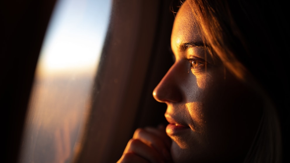 Young woman looks out of the airplane window: There are numerous myths about what you should consider when booking a flight - a new analysis has now disproved some of them