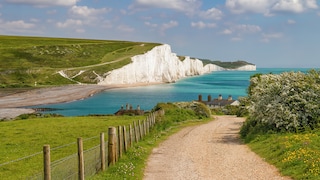 The England Coast Path passes by white cliffs, green meadows, and turquoise waters.