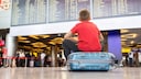Boy Sits on Suitcase at Airport and Waits
